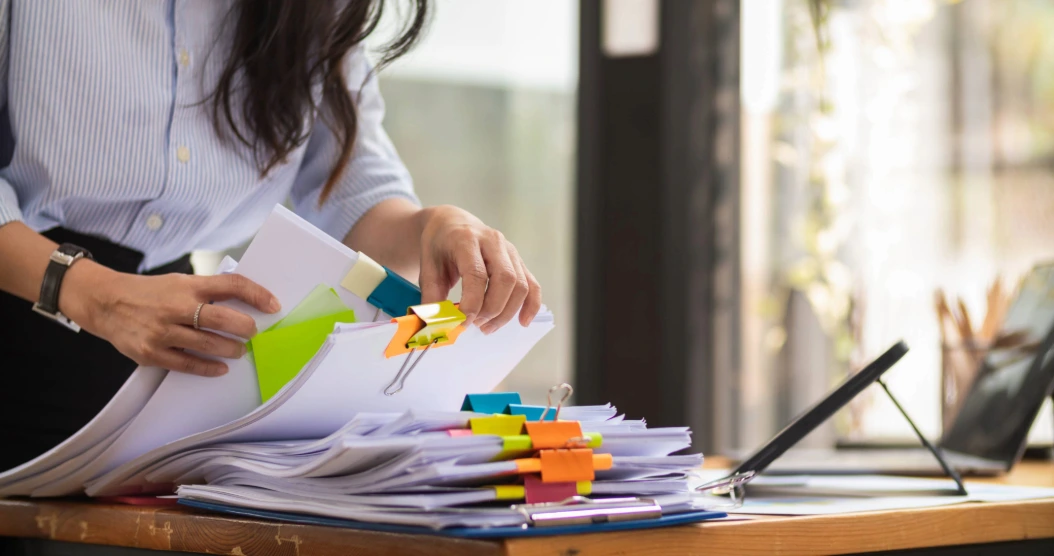 A senior staff member organises paper attendance records.